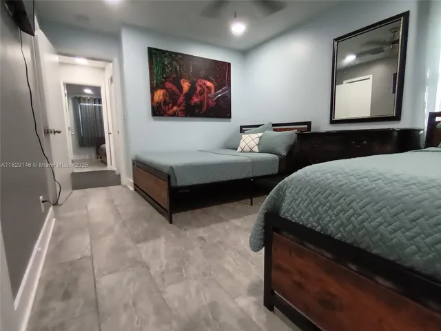 a bedroom with a bed a mirror on dresser and a flat screen tv