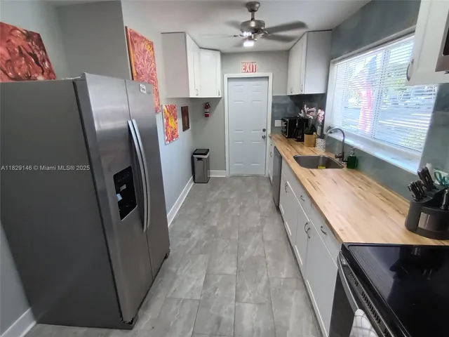 a kitchen with a sink dishwasher a stove and white cabinets with wooden floor