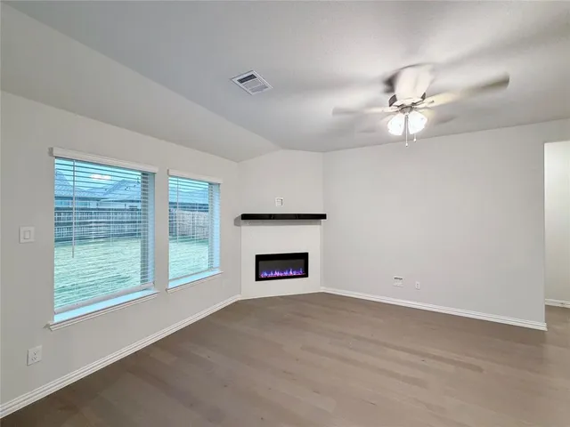 an empty room with windows fireplace and fan