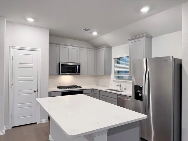 a kitchen with a refrigerator a stove a microwave and white cabinets
