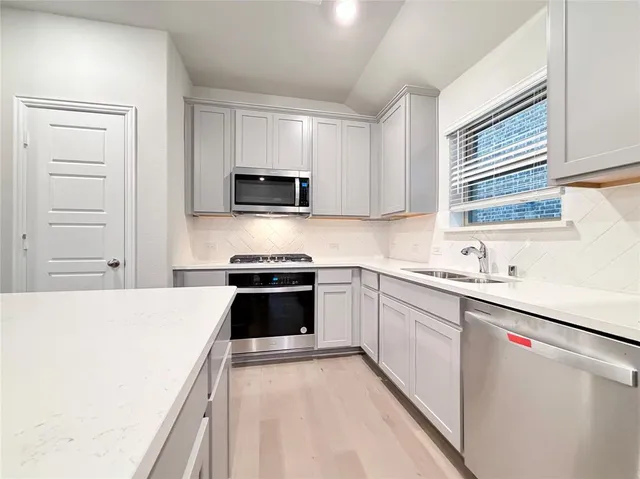 a kitchen with stainless steel appliances a sink stove refrigerator and cabinets