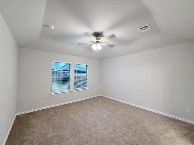 an empty room with a chandelier fan and windows
