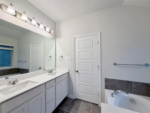 a spacious bathroom with a double vanity sink a mirror and a bathtub