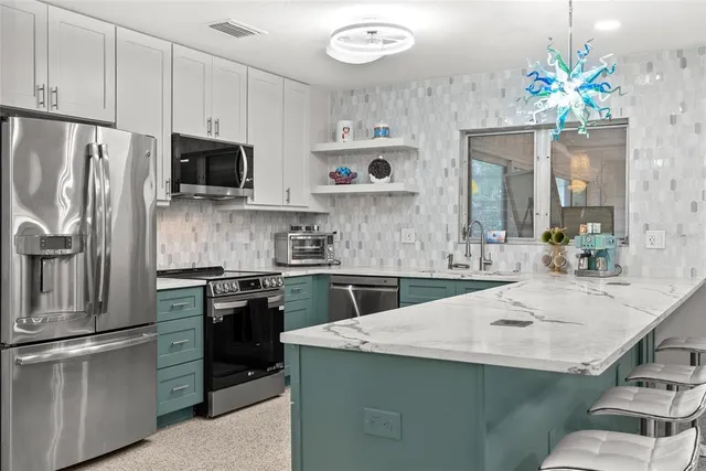 a kitchen with kitchen island granite countertop stainless steel appliances a sink stove top oven and refrigerator