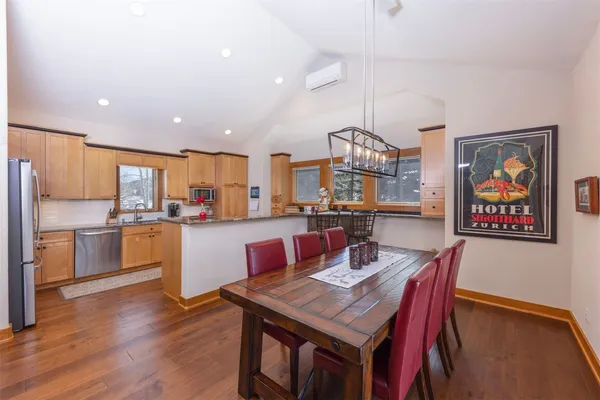 a open dining room with stainless steel appliances kitchen island granite countertop a dining table chairs and a refrigerator