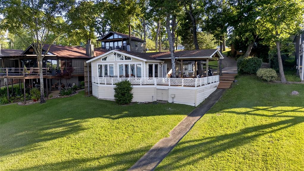 1113 Rim O The World Drive Tool, TX 75143 - Photo 32 of 40 Lakeside view of the waterfront residence featuring a spacious deck with white lattice railings, and a covered patio.
