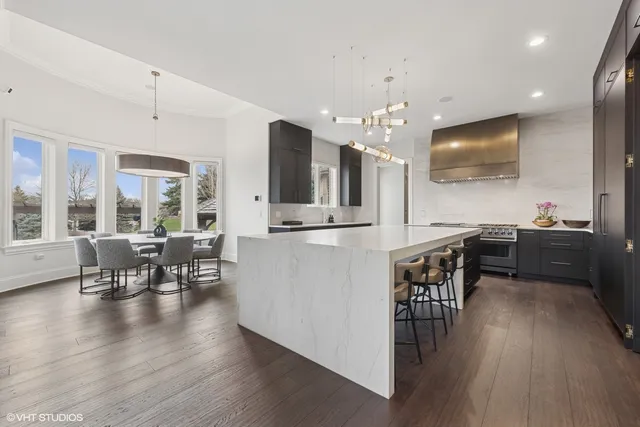 an open kitchen with granite countertop a stove a sink a dining table and chairs