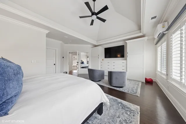 a bedroom with a bed a chandelier and flat screen tv