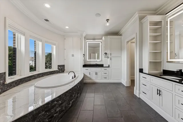 a bathroom with a granite countertop double vanity sink a mirror and a bathtub