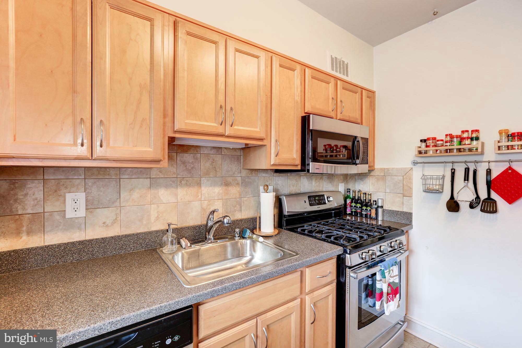 10002 Rogart Road Silver Spring, MD 20901 - Photo 10 of 28 a kitchen with stainless steel appliances granite countertop a sink a stove and a microwave