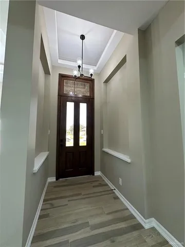 a view of a hallway with a chandelier and wooden floor