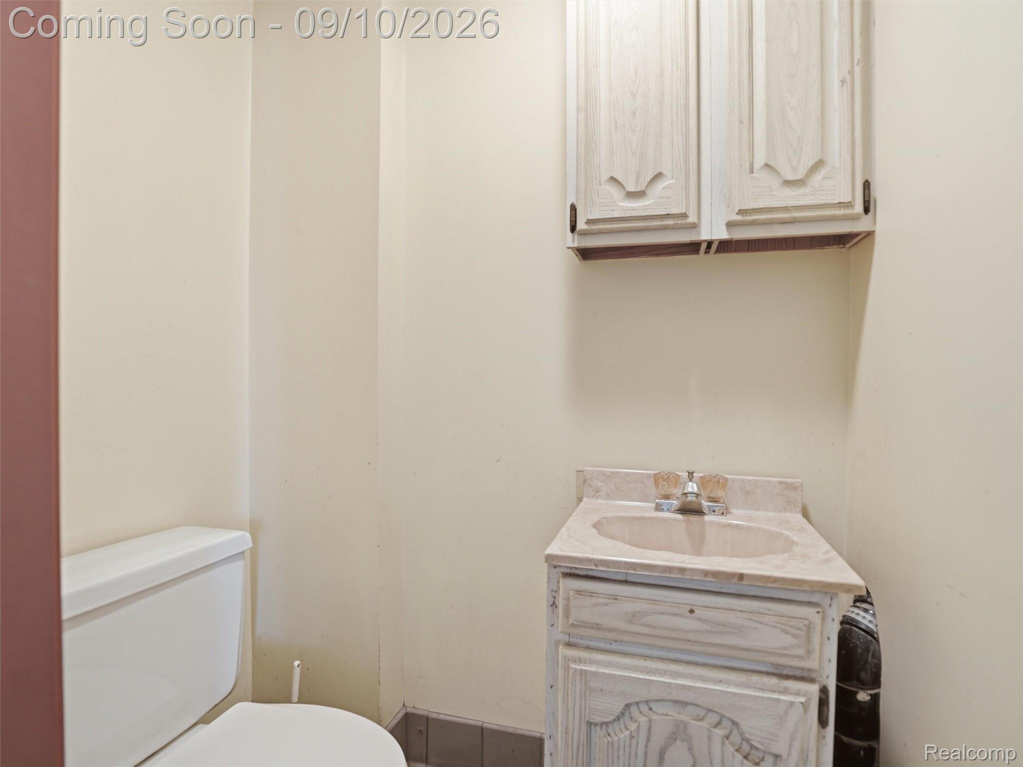 61400 Romeo Plank Road Ray, MI 48096 - Photo 53 of 99 White toilet, vanity with integrated sink, and upper wall-mounted cabinetry