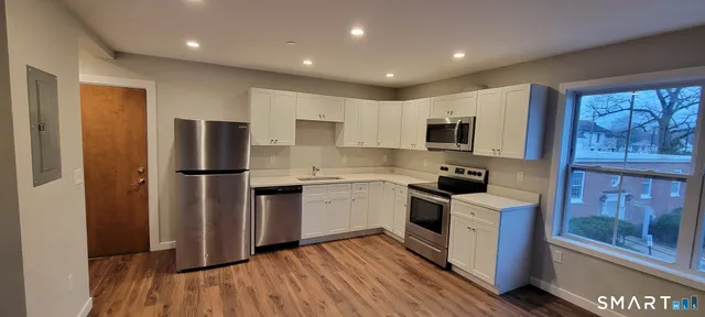 a kitchen with a refrigerator a stove top oven a sink dishwasher and wooden floor