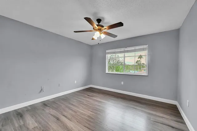 a view of an empty room with window and wooden floor