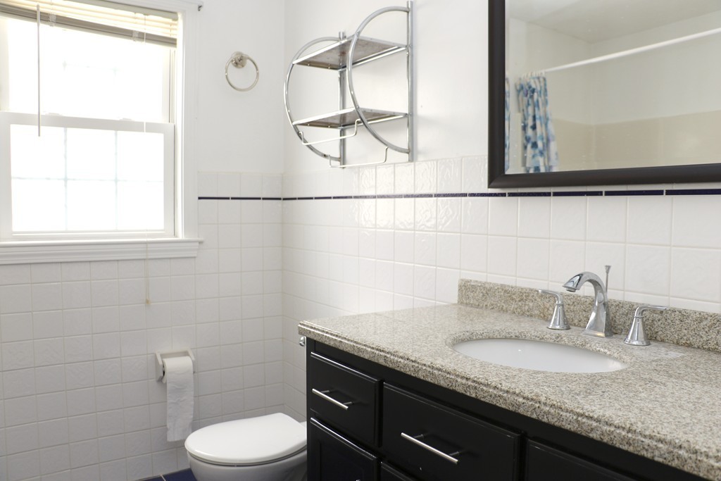 124 Maple Street, Unit 124 Needham, MA 02492 - Photo 13 of 16 a bathroom with a granite countertop sink a toilet and mirror