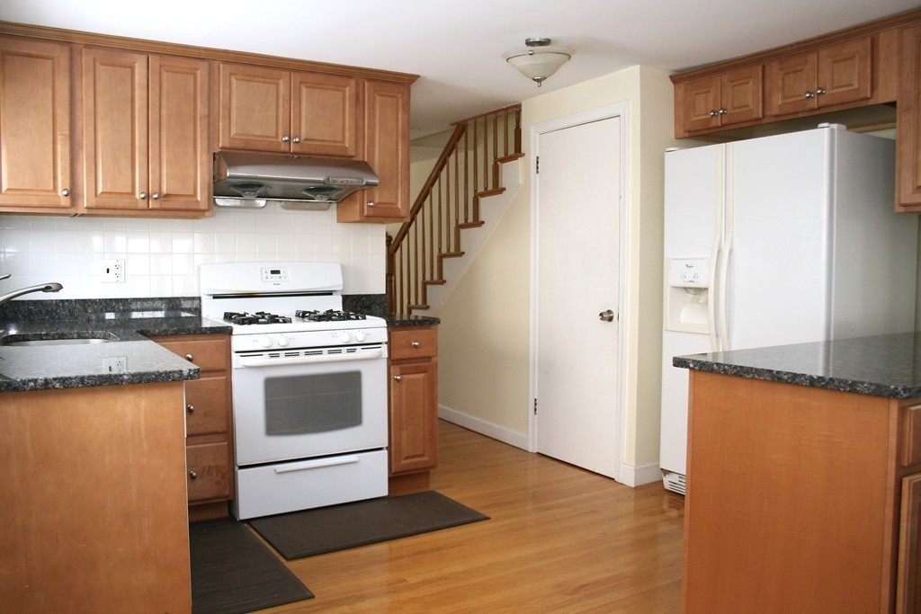 124 Maple Street, Unit 124 Needham, MA 02492 - Photo 8 of 16 a kitchen with granite countertop a refrigerator a sink and a stove