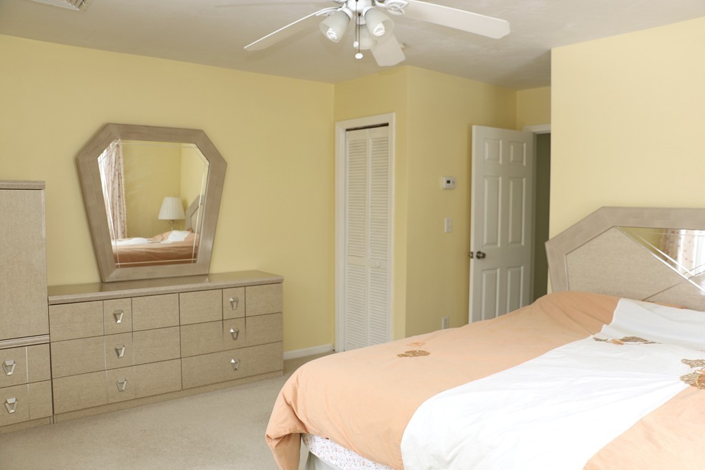 124 Maple Street, Unit 124 Needham, MA 02492 - Photo 10 of 16 a bedroom with a bed a mirror on dresser and a chandelier