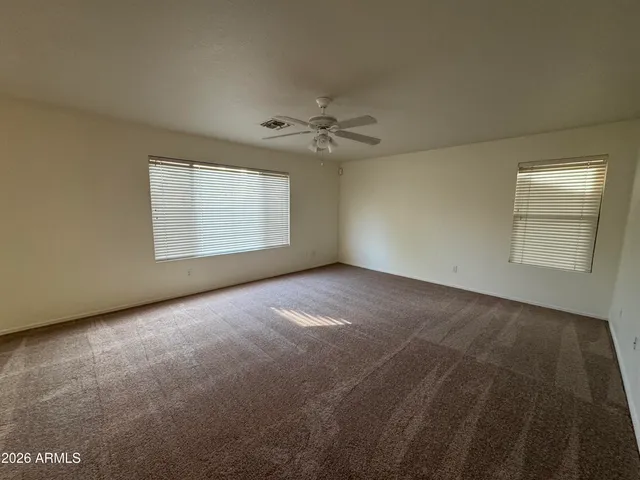 an empty room with windows and ceiling fan