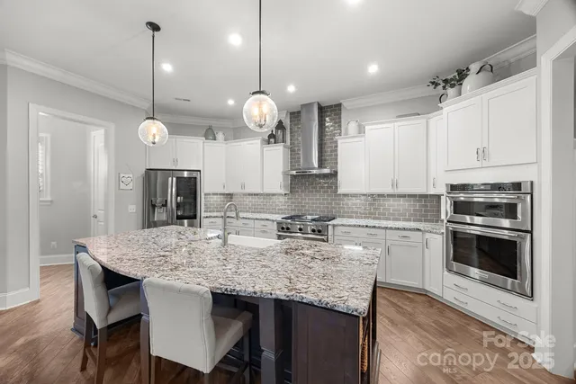 a kitchen with granite countertop a table chairs stainless steel appliances and wooden floor