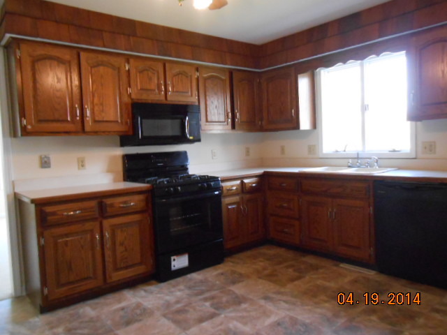 90 Long Beach Road Montgomery, IL 60538 - Photo 5 of 13 a kitchen with granite countertop a stove top oven a sink and dishwasher a refrigerator with wooden cabinets