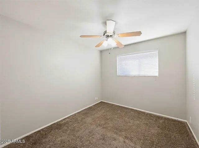 an empty room with a window and a fan
