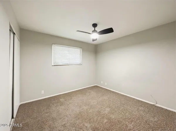 an empty room with a window and a fan