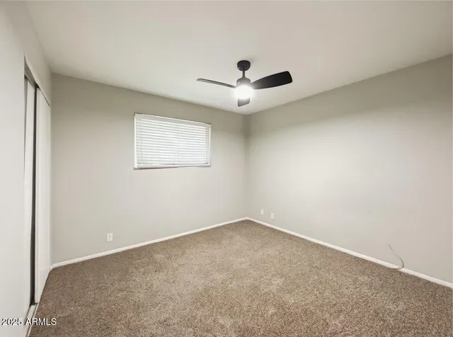 an empty room with a window and a fan