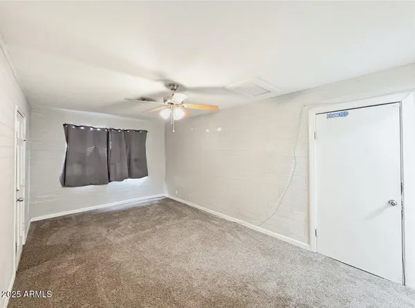 an empty room with a fan & a bathroom
