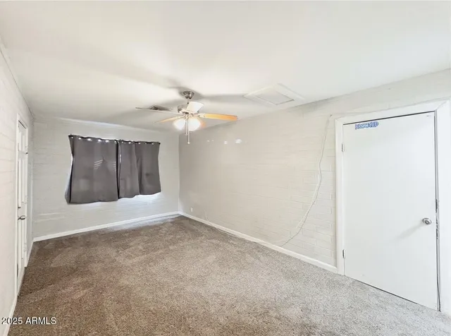 an empty room with a fan & a bathroom