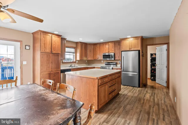 a kitchen with stainless steel appliances granite countertop a stove a refrigerator a sink and dishwasher with wooden floor