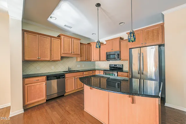 a kitchen with stainless steel appliances granite countertop a refrigerator a sink and white cabinets