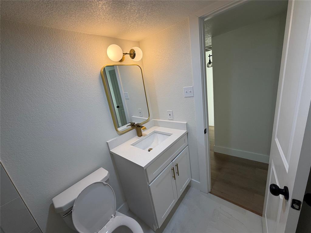 424 Valley Park Drive Garland, TX 75043 - Photo 17 of 18 a bathroom with a toilet a sink and mirror