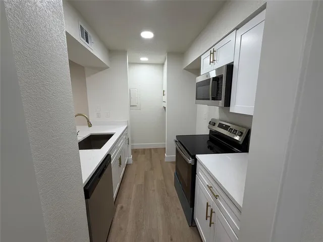 a kitchen with stainless steel appliances a stove microwave and sink