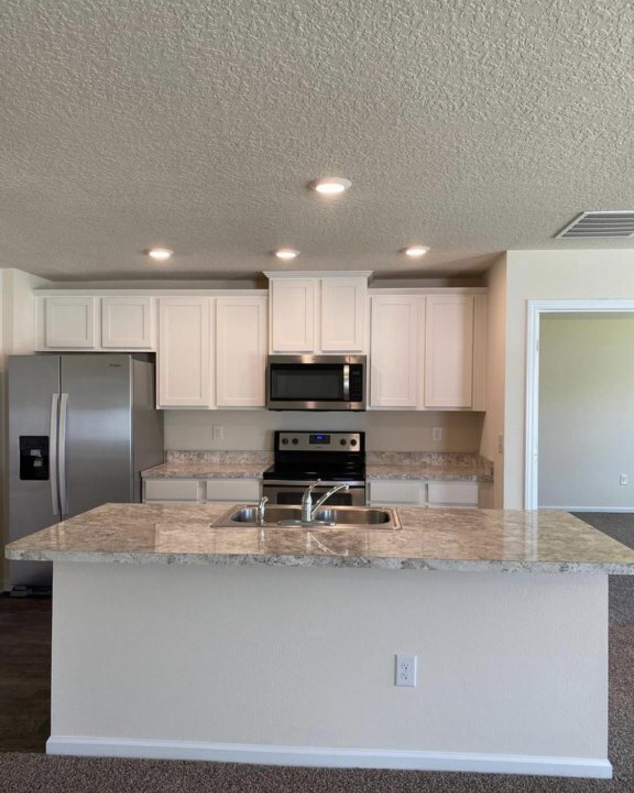 32 Del Mar Circle St. Augustine, FL 32086 - Photo 5 of 21 a kitchen with kitchen island granite countertop a sink a stove a refrigerator cabinets and a counter top space