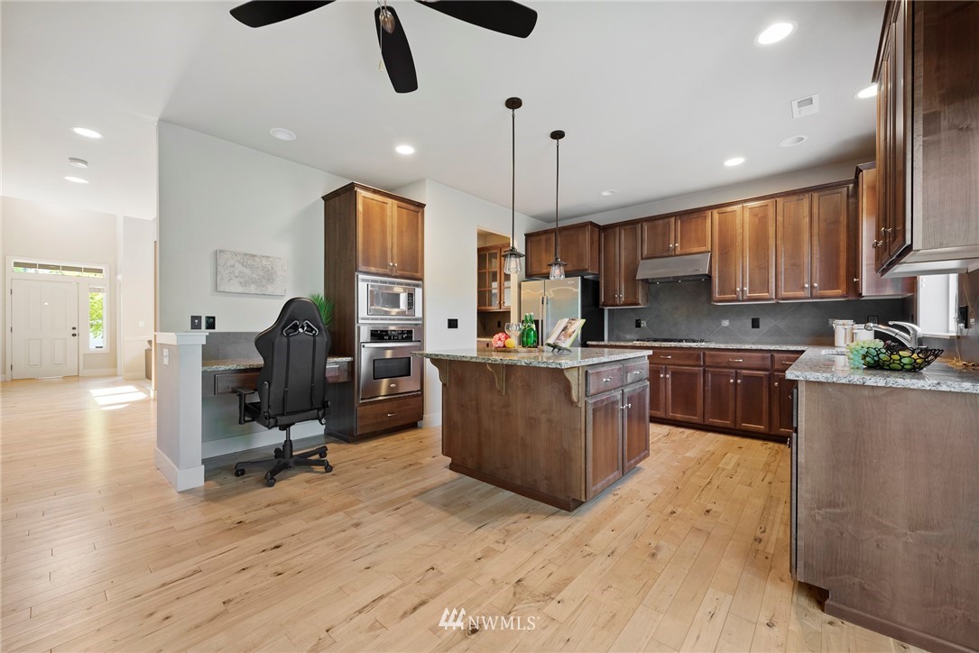 22832 36th Drive Southeast Bothell, WA 98021 - Photo 8 of 26 a kitchen with stainless steel appliances kitchen island granite countertop a stove top oven a sink a dining table and chairs with wooden floor