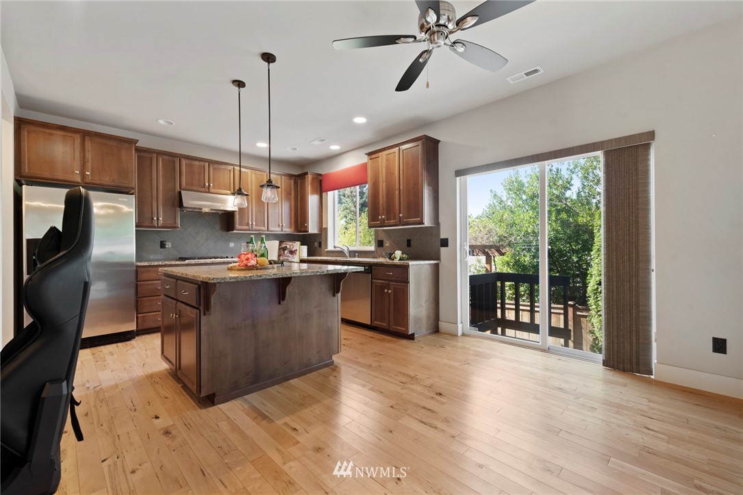 22832 36th Drive Southeast Bothell, WA 98021 - Photo 9 of 26 a kitchen with stainless steel appliances granite countertop a refrigerator a sink dishwasher a stove and a dining table with wooden floor