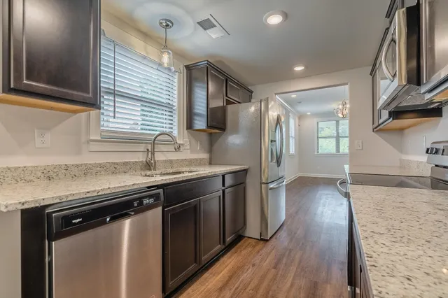 a kitchen with stainless steel appliances granite countertop a sink and wooden floor