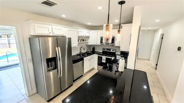a kitchen with stainless steel appliances a refrigerator a sink a stove a microwave oven a sink and cabinets