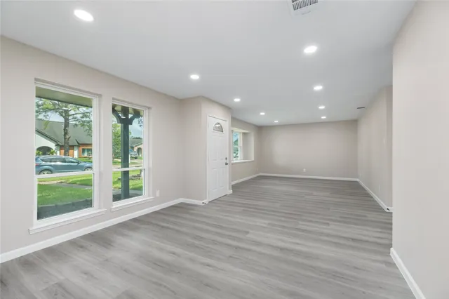 an empty room with wooden floor and windows