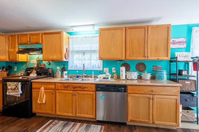 a kitchen with stainless steel appliances a refrigerator sink and wooden floor