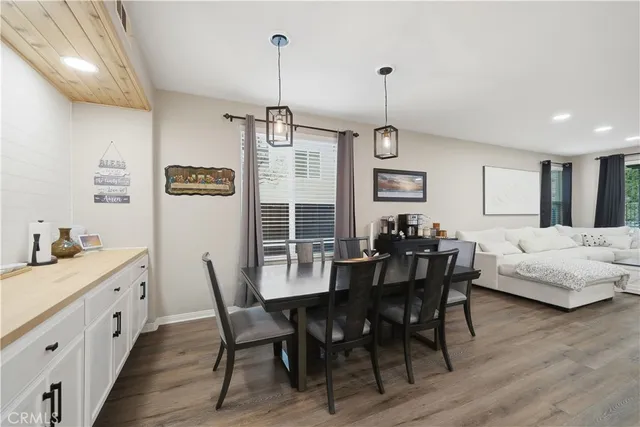 a view of a dining room and livingroom with furniture wooden floor a rug a fireplace and a chandelier