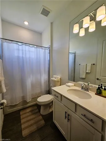a bathroom with a sink a toilet a mirror and shower