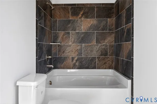 a bathroom with a granite countertop bathtub sink vanity mirror and toilet