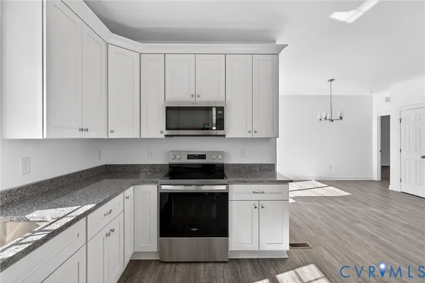 a kitchen with granite countertop white cabinets and stainless steel appliances