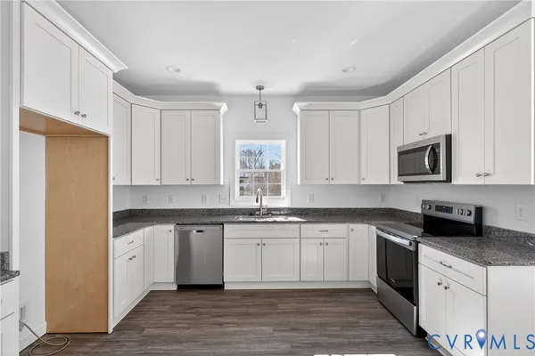 a kitchen with granite countertop white cabinets white appliances and sink