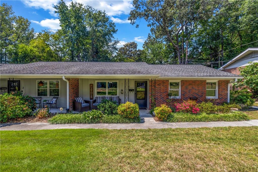 a front view of a house with lots of garden and porch
