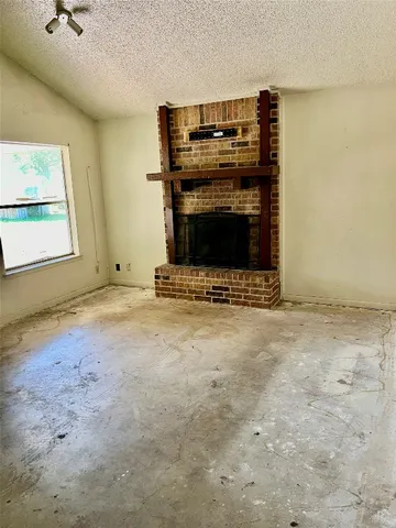 a view of an empty room with a fireplace and a window