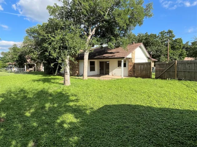 a view of a house next to a big yard and large trees