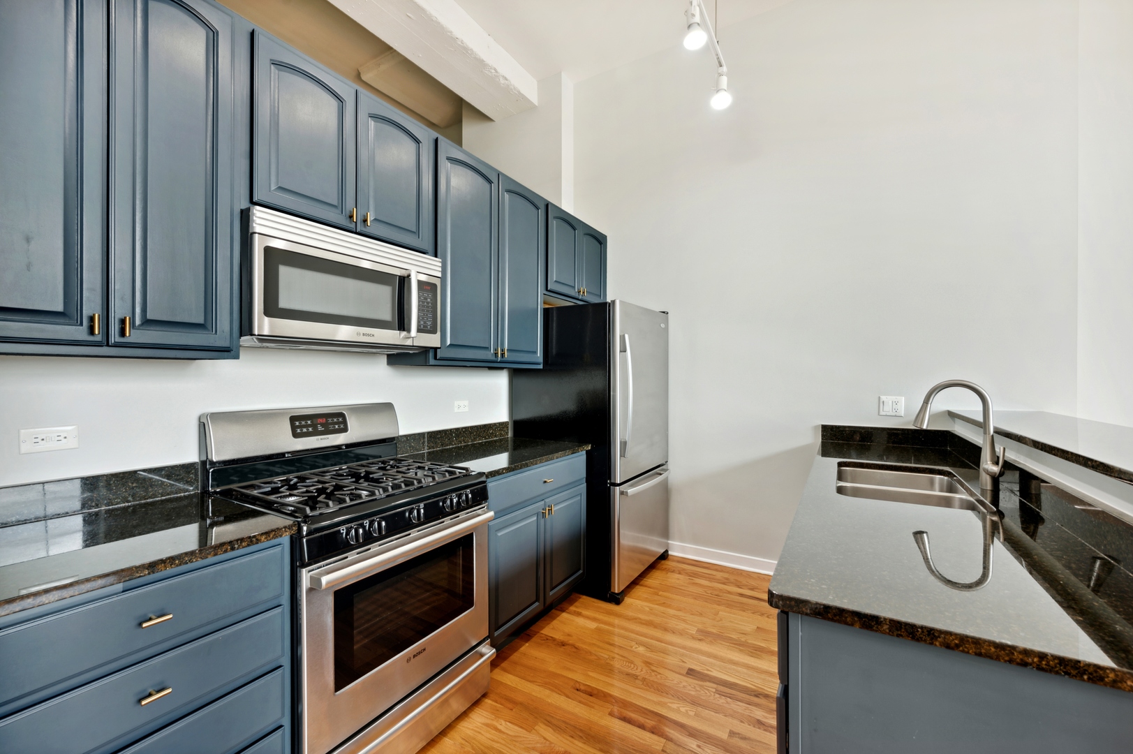 1224 West Van Buren Street, Unit 300 Chicago, IL 60607 - Photo 6 of 18 a kitchen with granite countertop stainless steel appliances a sink stove and microwave
