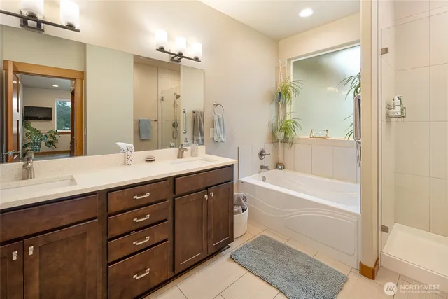 a bathroom with a tub sink double vanity and shower